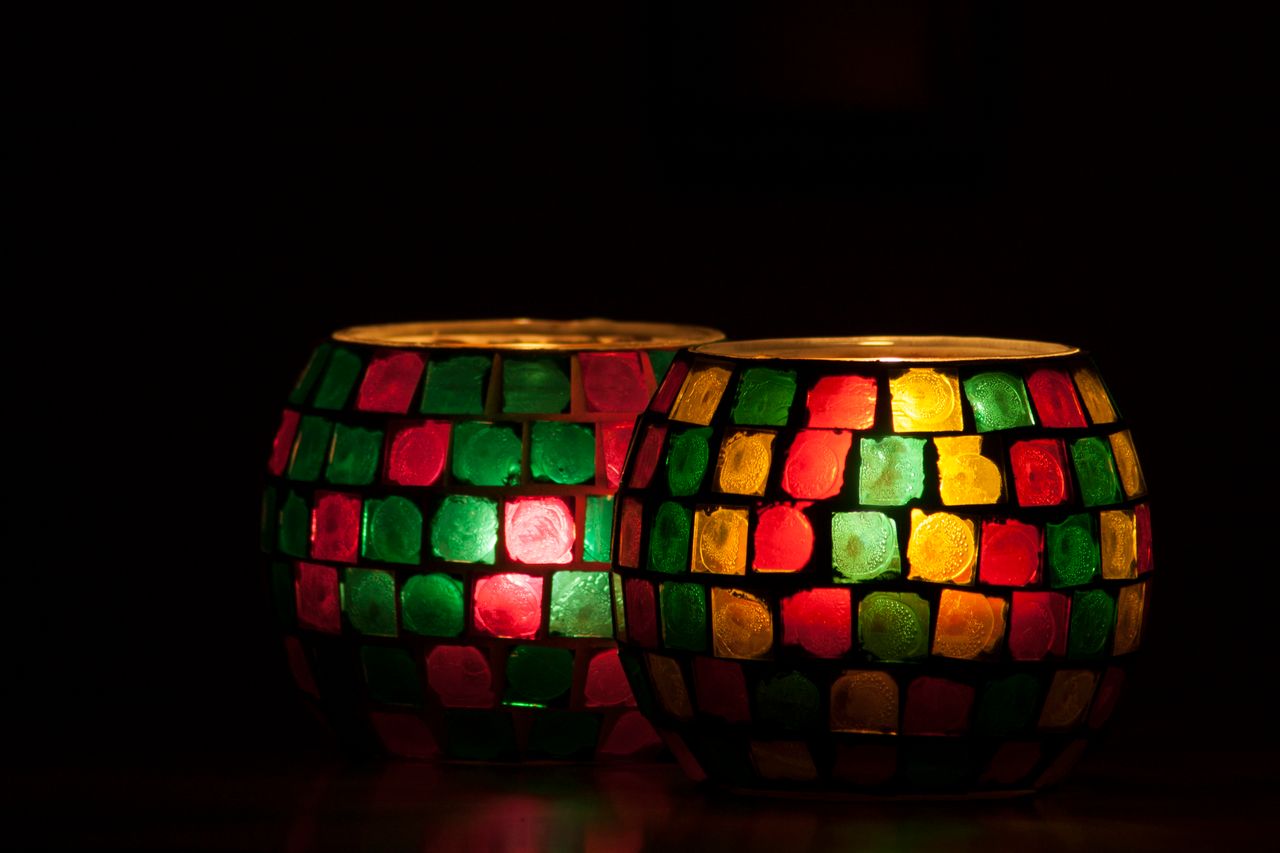 vision Vibrant mosaic candle holders glowing softly against a dark background, creating a warm and cozy atmosphere.