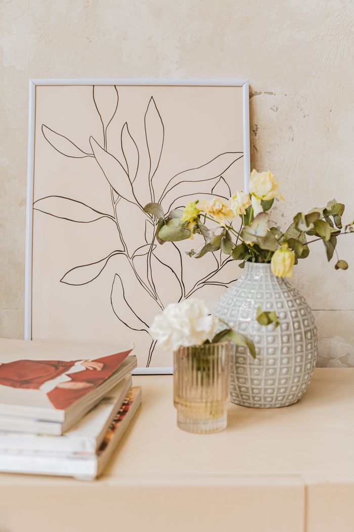 journey-01 A stylish display of a line art frame with vases and flowers on a wooden shelf for home decor inspiration.